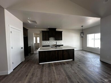 Kitchen featuring healthy amount of natural light, dark wood-style flooring, a center island with sink, dark brown cabinetry, and recessed lighting