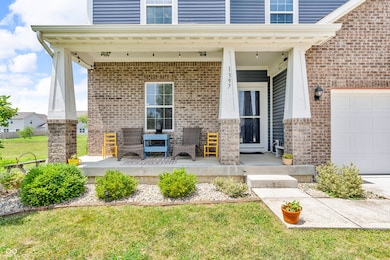 view of exterior entry featuring brick siding, a garage, a porch, and a lawn