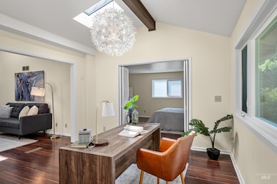 Home office with dark wood-type flooring, a skylight, and a chandelier
