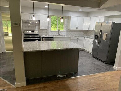 Kitchen featuring backsplash, white cabinetry, til