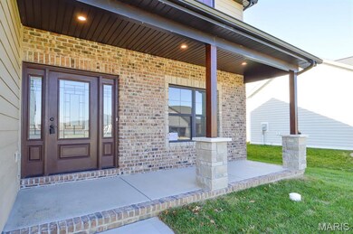 View of exterior entry featuring covered porch and brick siding