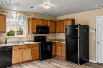 Kitchen with black appliances, light countertops, and light wood finished floors
