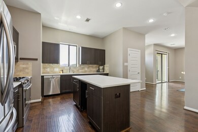 Kitchen featuring dark brown cabinets, stainless steel appliances, decorative backsplash, a kitchen island, and dark wood-style flooring