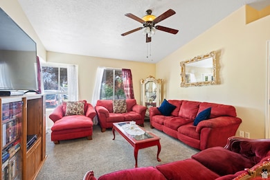 Carpeted living room with a textured ceiling and ceiling fan