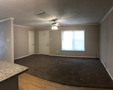 Unfurnished living room featuring crown molding, wood finished floors, a ceiling fan, a textured ceiling, and carpet