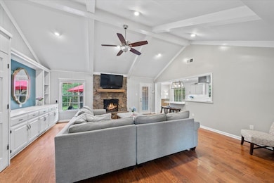 Living room with a fireplace, a ceiling fan, light wood finished floors, baseboards, and recessed lighting