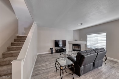 Living area with a textured ceiling, stairs, wood