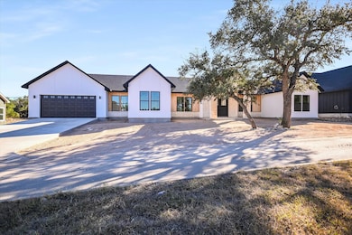 Modern farmhouse style home with driveway, an attached garage, and a shingled roof