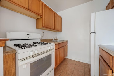 Kitchen with white appliances, light tile patterned floors, and light countertops