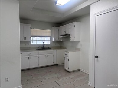 Kitchen with white cabinetry, light countertops, and under cabinet range hood