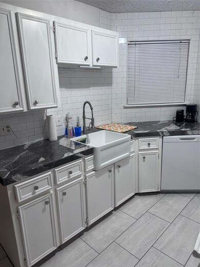 Kitchen with backsplash, white cabinetry, a sink,