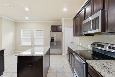 Kitchen featuring appliances with stainless steel finishes, dark brown cabinetry, light stone counters, decorative backsplash, and ornamental molding
