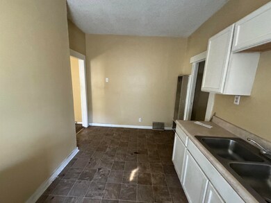 Kitchen with a textured ceiling, white cabinetry, 