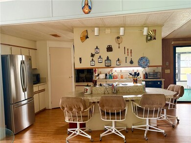 Kitchen featuring freestanding refrigerator, light countertops, light wood-style flooring, a kitchen bar, and wooden walls