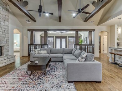 Living room with light hardwood / wood-style floors, a fireplace, ceiling fan, and beamed ceiling