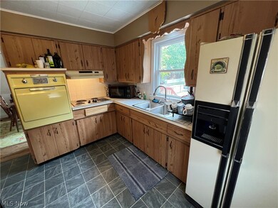 Kitchen with white electric stovetop, fridge, oven, sink, and dark tile floors