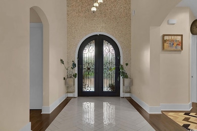 Foyer featuring arched walkways, french doors, a towering ceiling, and wood finished floors