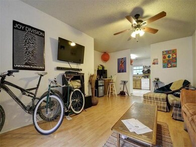 Living room featuring light wood finished floors, a textured ceiling, and ceiling fan