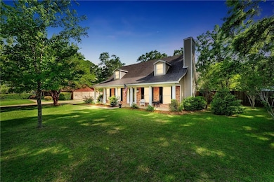 View of front facade featuring covered porch, brick siding, fence, and a front lawn