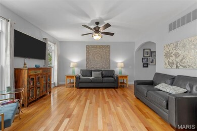 Living room with light wood-style floors, ceiling fan, and arched walkways