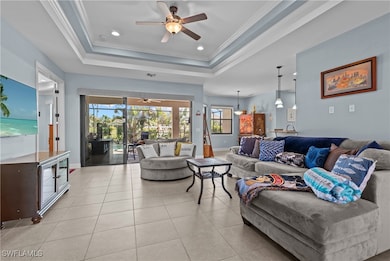Living room with double tray ceiling, tile floors, crown molding, and sliders leading to the pool