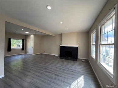 Unfurnished living room with recessed lighting, a brick fireplace, and dark wood finished floors