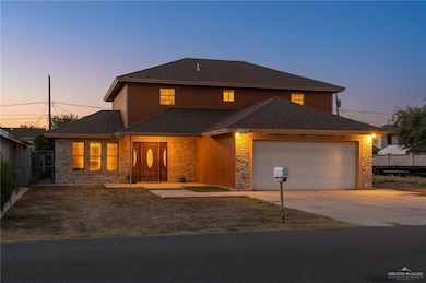 Traditional-style house featuring an attached garage, concrete driveway, stone siding, and roof with shingles