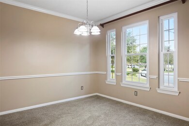 You may be inspired to wine and dine your friends and family more often with this elegant formal dining room. This space features plush neutral carpet and paint, chair and crown molding, a stylish chandelier and soft natural light with views of the front yard.