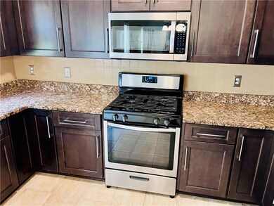 Kitchen with appliances with stainless steel finishes, tasteful backsplash, dark brown cabinetry, and light stone counters