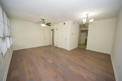 Unfurnished living room with a chandelier, wood finished floors, and ceiling fan