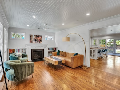 A cozy fireplace, built-in bookshelves, and warm hardwood floors. The open layout flows into a modern kitchen with bar seating. Large windows provide plenty of natural light.