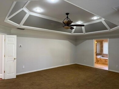 Unfurnished room with crown molding, dark colored carpet, ceiling fan, and coffered ceiling