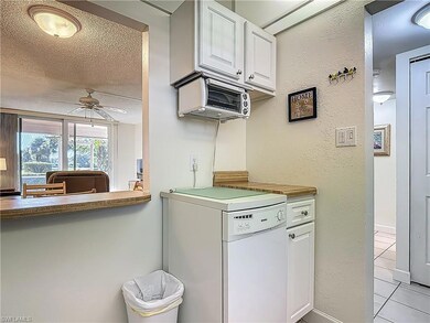 Kitchen featuring fridge, ceiling fan, light tile patterned flooring, a textured ceiling, and white cabinetry