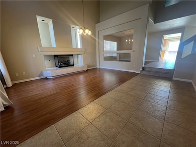 Unfurnished living room featuring wood finished floors, a chandelier, a high ceiling, and a tiled fireplace