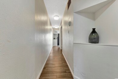Corridor featuring a textured wall, baseboards, a 