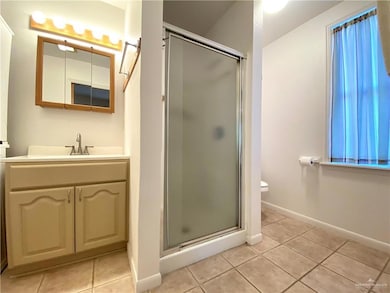Bathroom featuring light tile patterned floors, vanity, and a stall shower