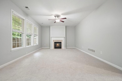 Unfurnished living room with ceiling fan, light carpet, and a fireplace with flush hearth