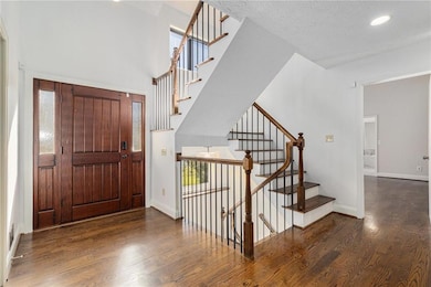 Foyer with dark wood-style floors, stairs, recessed lighting, healthy amount of natural light, and a textured ceiling