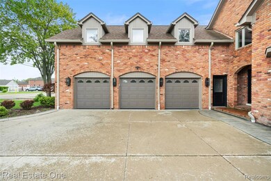 View of front of home with driveway, a shingled roof, a garage, and brick siding