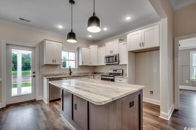 Kitchen featuring dark wood-style flooring, ornamental molding, visible vents, and stainless steel appliances