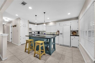Kitchen with dark countertops, white appliances, white cabinets, light tile patterned floors, and recessed lighting