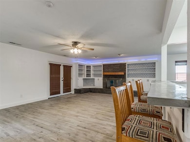Living area with ceiling fan, wood finished floors, and a brick fireplace