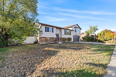 Split foyer home featuring concrete driveway, an attached garage, and brick siding