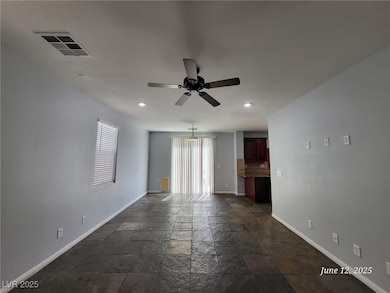 Empty room featuring stone tile floors, ceiling fa