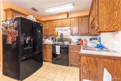 Kitchen featuring backsplash, light tile patterned floors, and black appliances