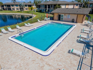 Community pool with a patio, fence, a water view,