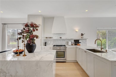 Kitchen featuring wall chimney range hood, a sink,