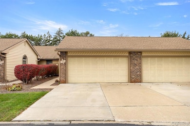 View of front of home with a shingled roof, brick siding, a garage, and driveway