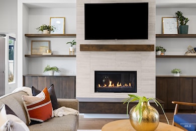 Living room featuring wood finished floors, a fireplace, and built in features
