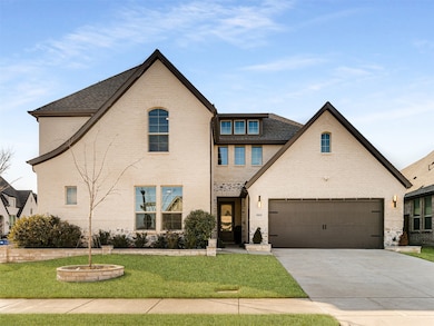 View of front of house featuring brick siding, driveway, a garage, and a front lawn